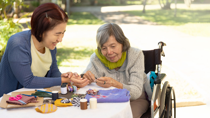 Caregiver and someone with late stage dementia doing crafts together